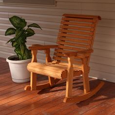 a wooden rocking chair next to a potted plant