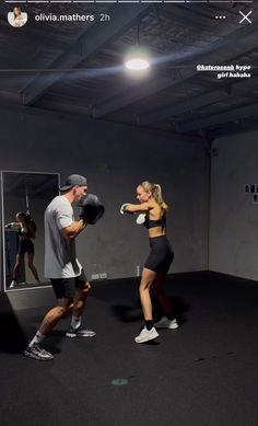 a man and woman practicing boxing in an empty gym room with mirrors on the wall