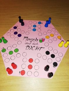 a pink board game sitting on top of a wooden table covered in lots of different colored buttons