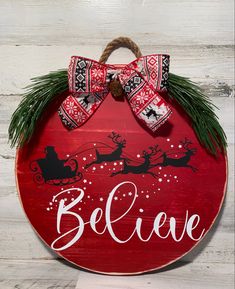 a red wooden sign that says believe with santa's sleigh on it