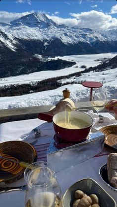 a table topped with plates and bowls filled with food next to a snow covered mountain