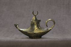 an old brass teapot with curved handles on a gray background is seen in this image