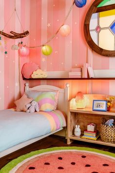 a child's bedroom decorated in pink, blue and green with striped wallpaper