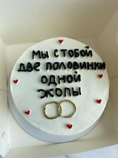 a cake with two wedding rings on it and the words in russian are spelled by small hearts