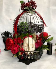 a birdcage filled with flowers and skulls sitting on top of a white table