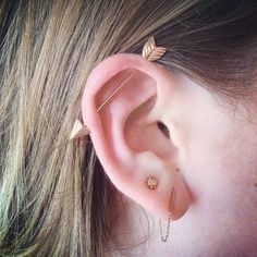 a close up of a person's ear with two piercings on it and one behind the ear