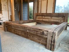 a bed frame made out of wood in a room with unfinished walls and flooring