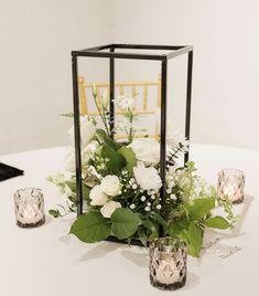 white flowers and greenery are arranged on a table