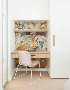 a bedroom with a bed, desk and chair next to a wallpapered closet