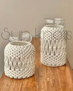 two white crocheted jars sitting on top of a wooden table