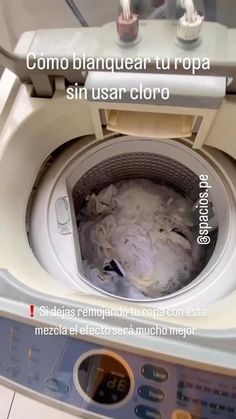 a washing machine with the door open and dirty clothes in it's front compartment