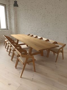 a wooden table and chairs in an empty room with white brick wall, windows and wood flooring