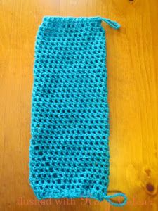 a blue crocheted bag sitting on top of a wooden table