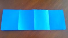 three folded pieces of blue paper sitting on top of a wooden table