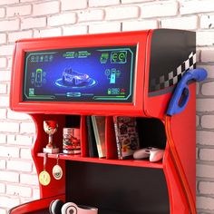 a red arcade machine sitting on top of a table next to a white brick wall