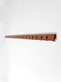 a wooden ruler with holes in it on a white surface, hanging from the wall