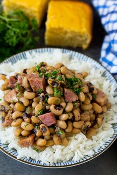 a white plate topped with beans and meat on top of rice next to buttered bread