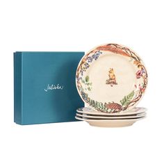 a set of four dinner plates in a gift box with the lid open to show it's design