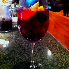 a glass filled with liquid sitting on top of a counter next to a wooden table