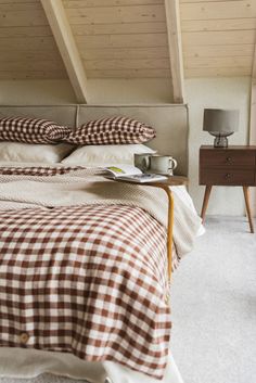 a bed sitting under a wooden ceiling next to a night stand with a lamp on it