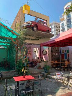 a red car is parked on top of the roof of a building with tables and chairs