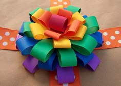 a colorful flower made out of paper sitting on top of a piece of cardboard with polka dots