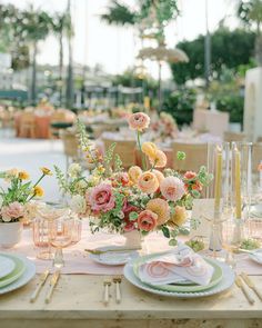 the table is set with flowers and place settings for an elegant dinner or party in pastel colors