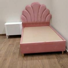 a pink bed with a shell shaped headboard and foot board