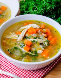 chicken vegetable soup with quinoa in a white bowl on a red and white checkered tablecloth