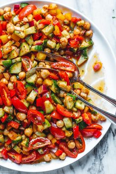 a white plate topped with lots of veggies on top of a marble table