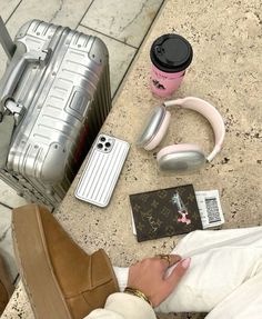 a woman sitting on the ground with her feet up next to some luggage and headphones