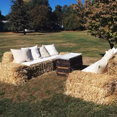 hay bales are stacked on top of each other in the grass near a couch and coffee table