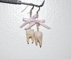 two tooth shaped earrings hanging from a hook