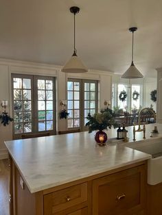 a large kitchen with an island in the middle and two lights hanging from the ceiling