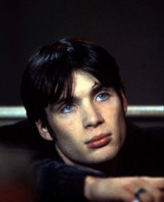 a young man with blue eyes holding a white object in his hand and looking at the camera