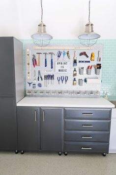 the cabinets are organized with tools and magnets on the pegboard behind them, along with two hanging lights