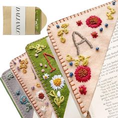 three pieces of fabric with flowers and letters on them are next to an open book