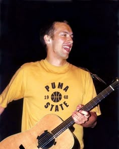 a man holding a guitar and singing into a microphone