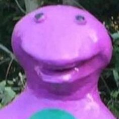 a purple dinosaur statue sitting next to a tree