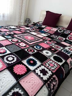 a bed covered in a multicolored crocheted blanket next to a window