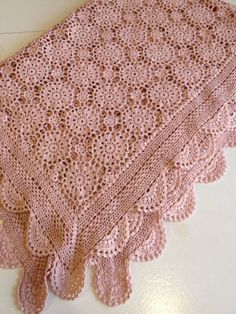 a pink crocheted table cloth on a white surface