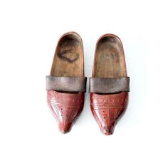 This is a pair of antique wooden clogs. The hand-carved wood sabot feature a red lacquer paint with leather straps across the arch. Vintage Closed Toe Mules With Leather Sole, Traditional Closed Toe Clogs, Traditional Brown Slip-on Clogs, Traditional Leather Clogs With Closed Toe, Traditional Leather Closed-toe Clogs, Traditional Closed Toe Clogs With Leather Sole, Traditional Leather Closed Toe Clogs, Traditional Leather Clogs With Rubber Sole, Traditional Slip-on Clogs With Rubber Sole