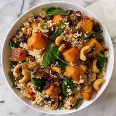 a white bowl filled with rice and vegetables on top of a marble countertop next to a wooden spoon