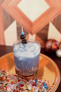 a candle is sitting on top of a plate with confetti and blue liquid