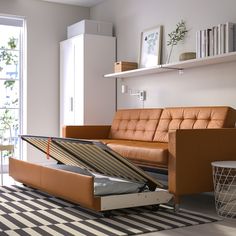 a living room with a couch, chair and open storage box on the floor in front of a sliding glass door