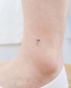 a small blue arrow tattoo on the ankle