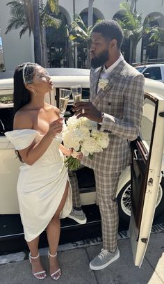 a man in a suit and tie standing next to a woman in a white dress