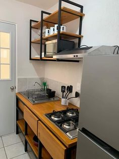 a small kitchen with stainless steel appliances and wooden counter tops, along with shelves above the stove