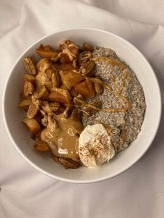 a white bowl filled with oatmeal, potatoes and gravy on top of a white cloth