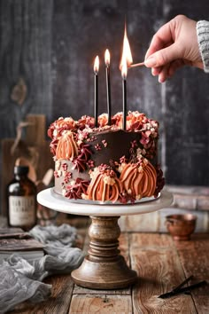 a person lighting candles on a cake with chocolate frosting and sprinkles